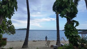 Ein Strand mit Palmen, einem Stuhl und einer Person beim Angeln.