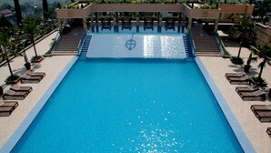 A large rectangular pool with clear blue water, surrounded by lounge chairs and steps leading down to the pool. - Royal Senyiur Hotel Pasuruan (Prigen)