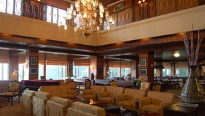 A spacious lobby with multiple seating areas, a chandelier, and large windows providing natural light. - Royal Senyiur Hotel Pasuruan (Prigen)