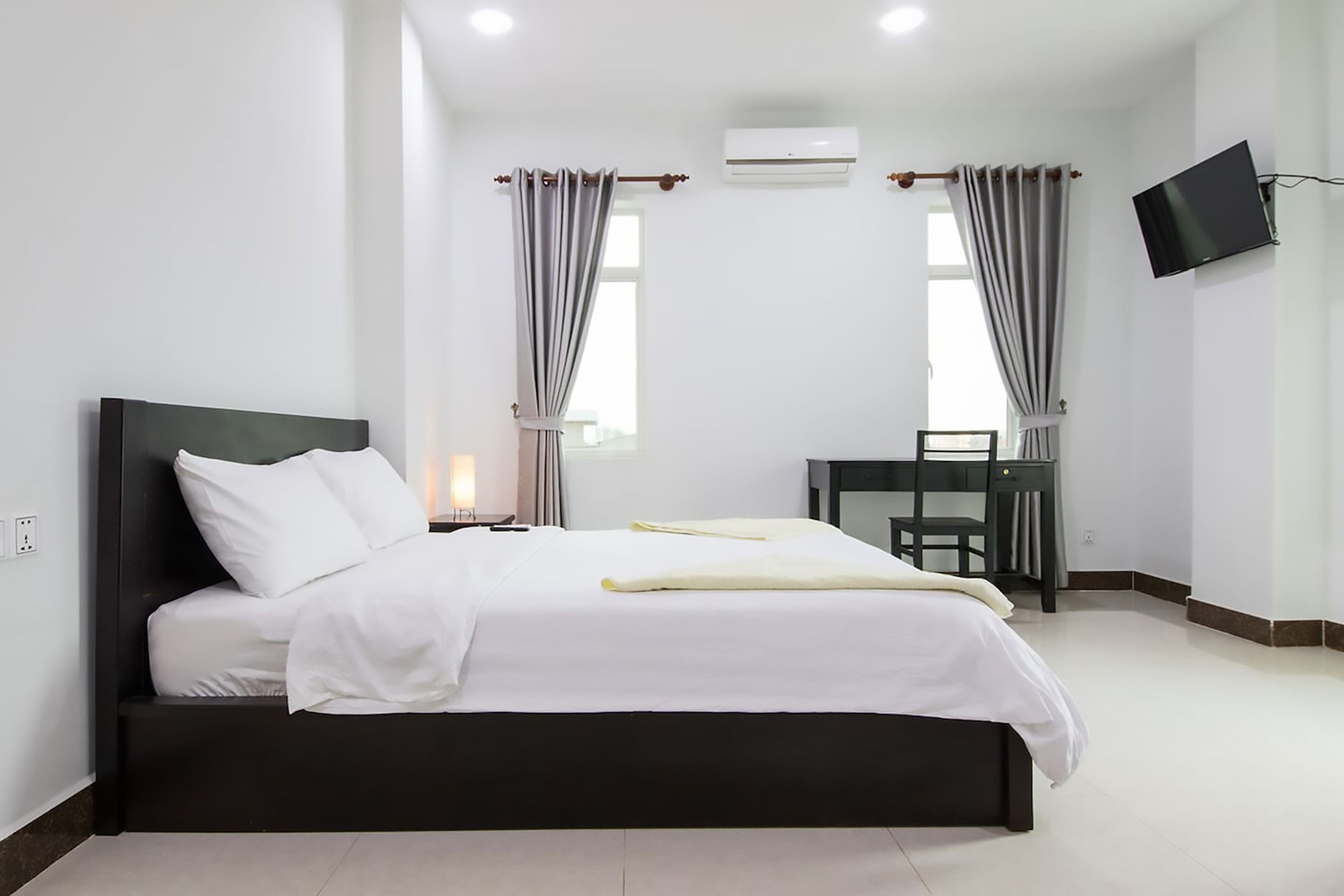 Een moderne hotelkamer met een groot bed, een bureau en een flatscreen televisie.