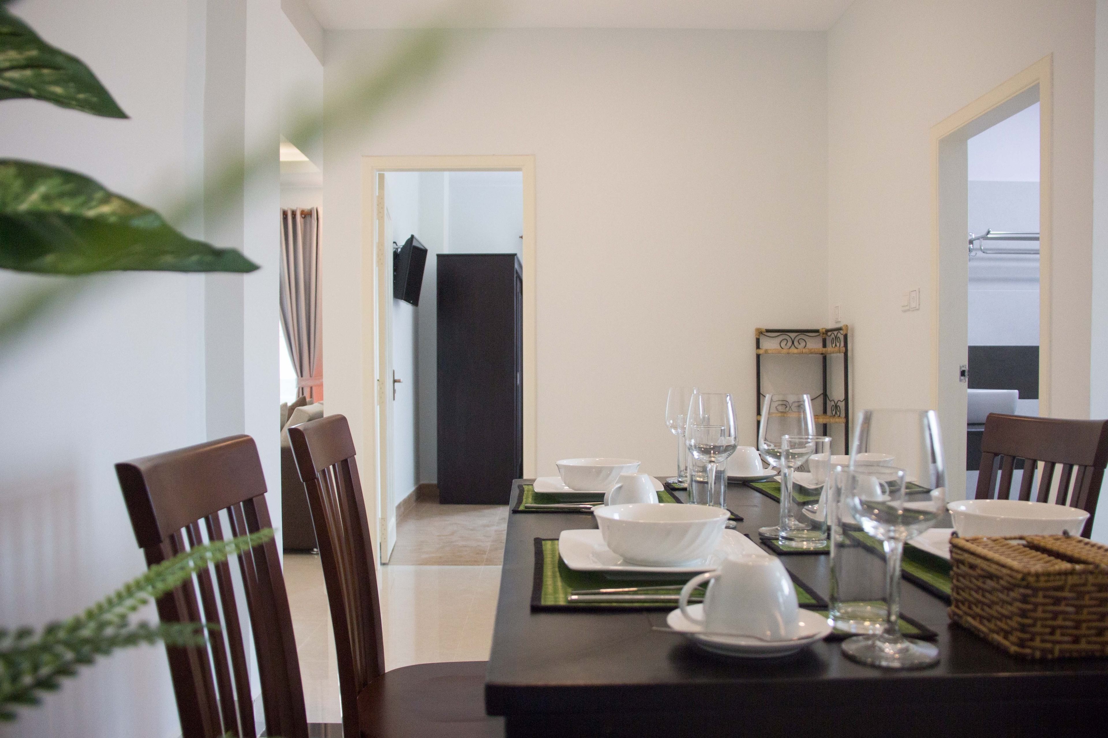 A dining area with a table set for four, chairs, and a view into another room.