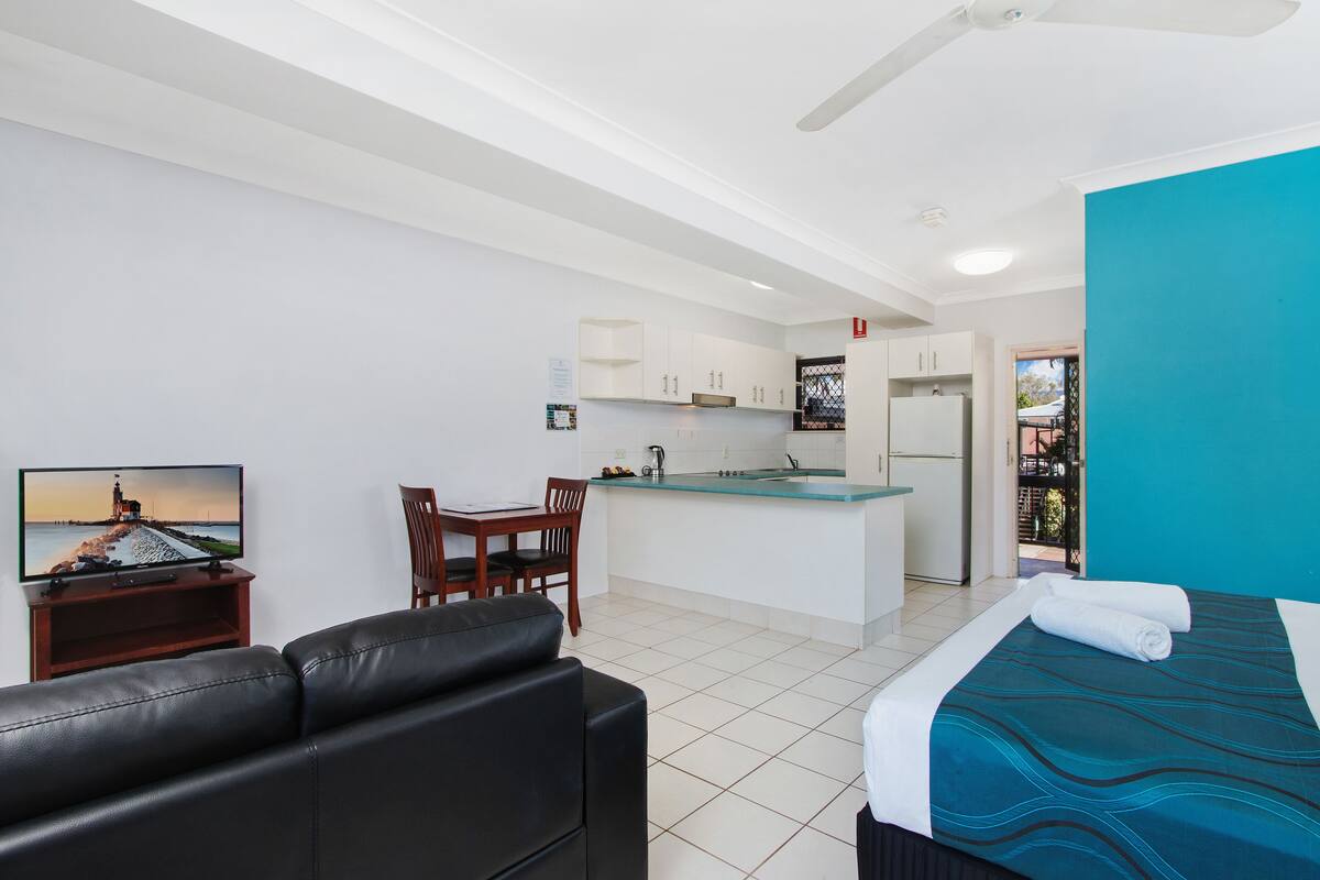 Een moderne hotelkamer met een bed, televisie, een eethoek en een keuken.