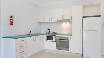 Una cocina moderna con armarios blancos, un refrigerador de acero inoxidable, un microondas y un horno.