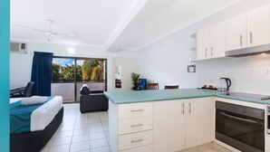 A modern hotel room with a balcony, a kitchenette, and a dining area. - Cairns City Palms (Cairns North)