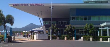 A modern airport terminal with a clear sky and mountains in the background.