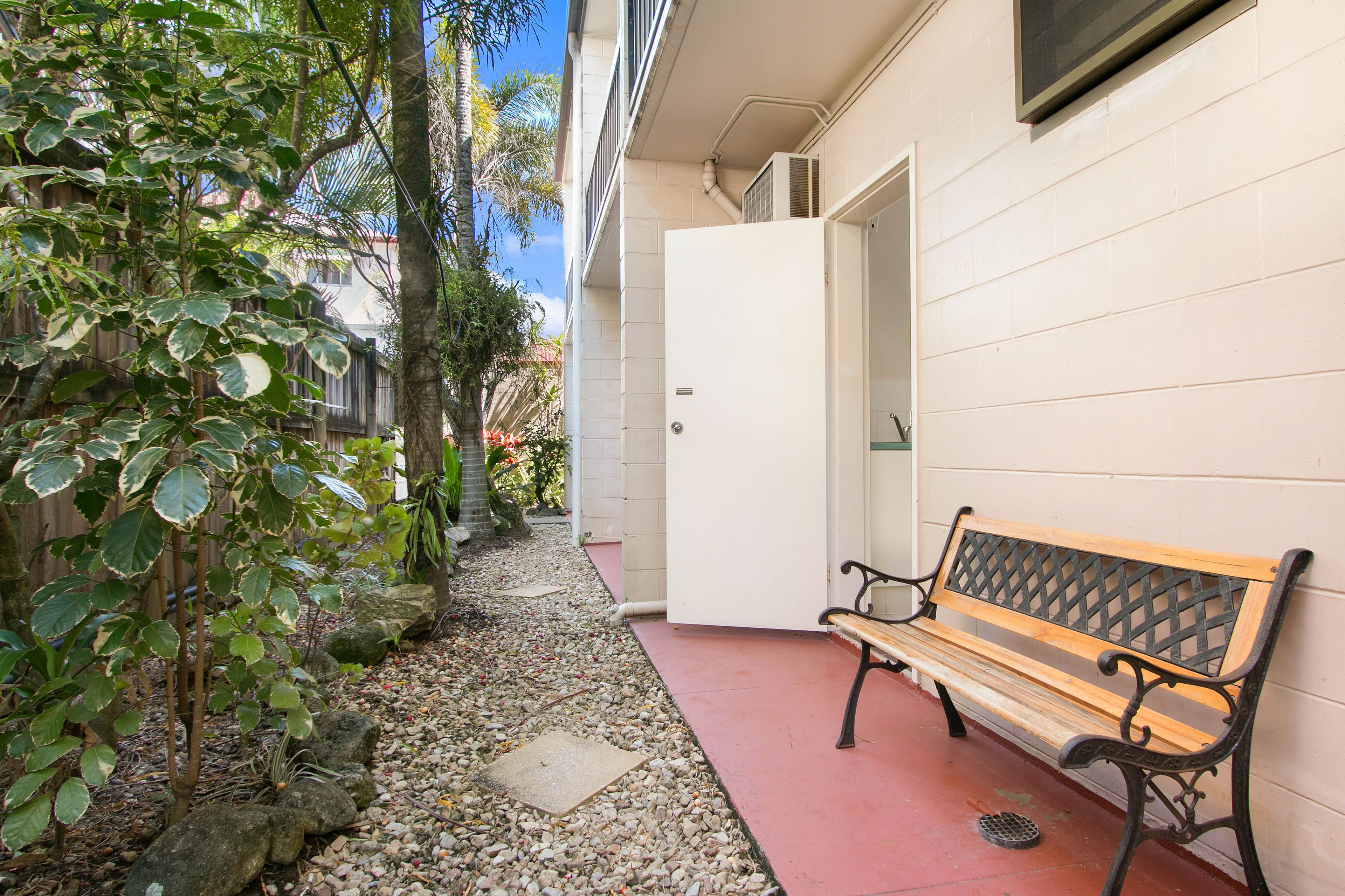 A narrow pathway with a bench, a door, and a wall with a window.