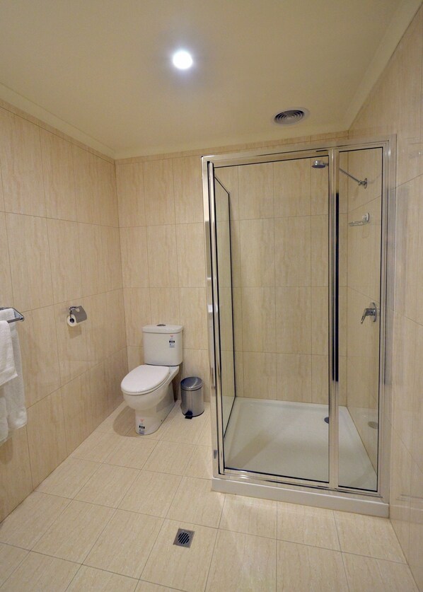 Un baño moderno con ducha de vidrio, inodoro y un cubo de basura.