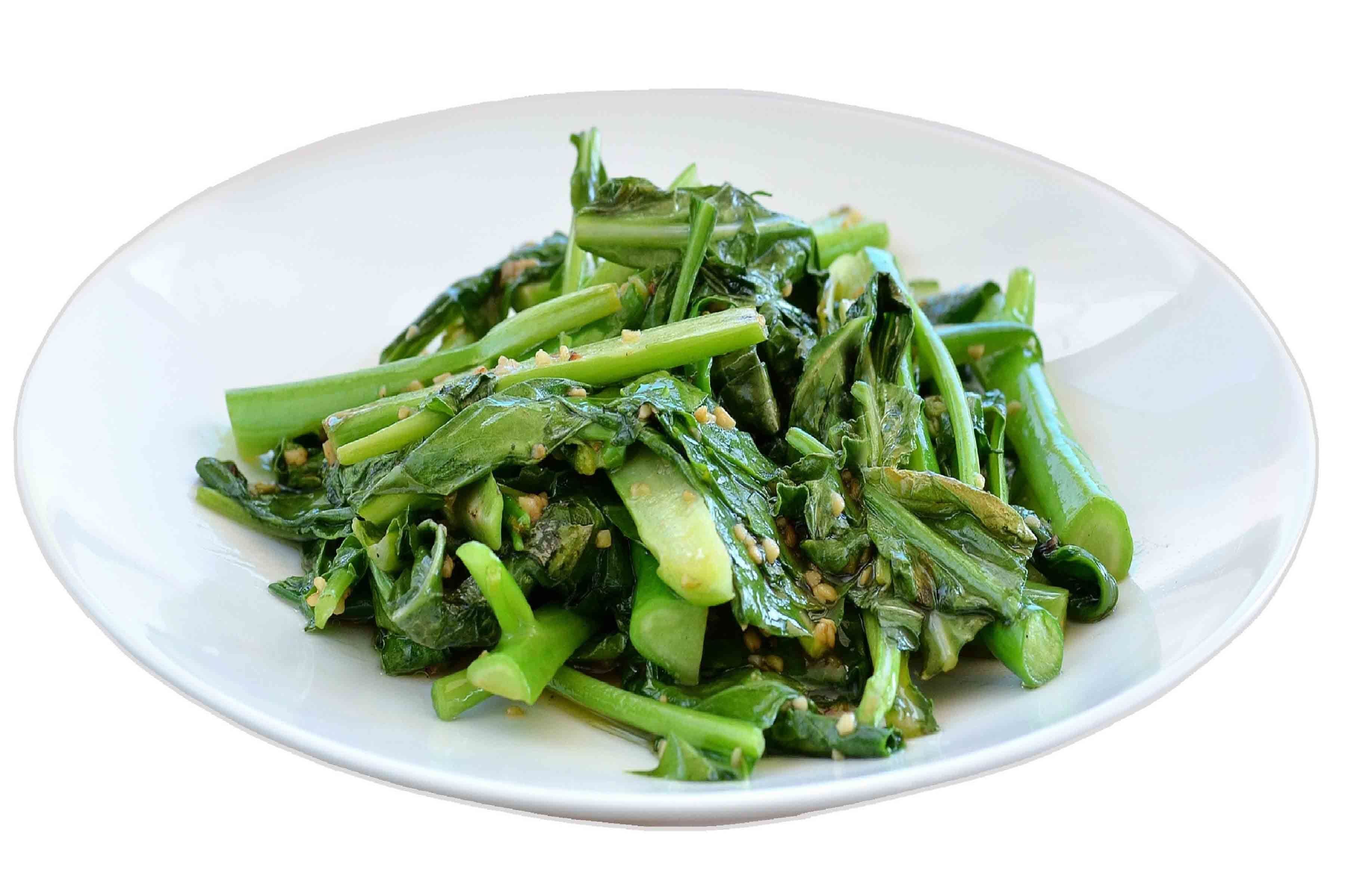 A white plate with cooked green leafy vegetables.