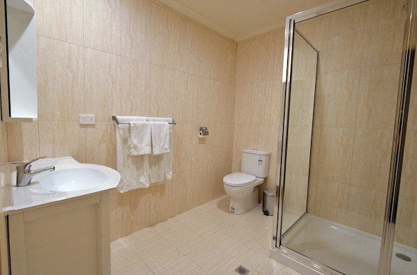 Un baño moderno con ducha de vidrio, lavamanos y retrete.