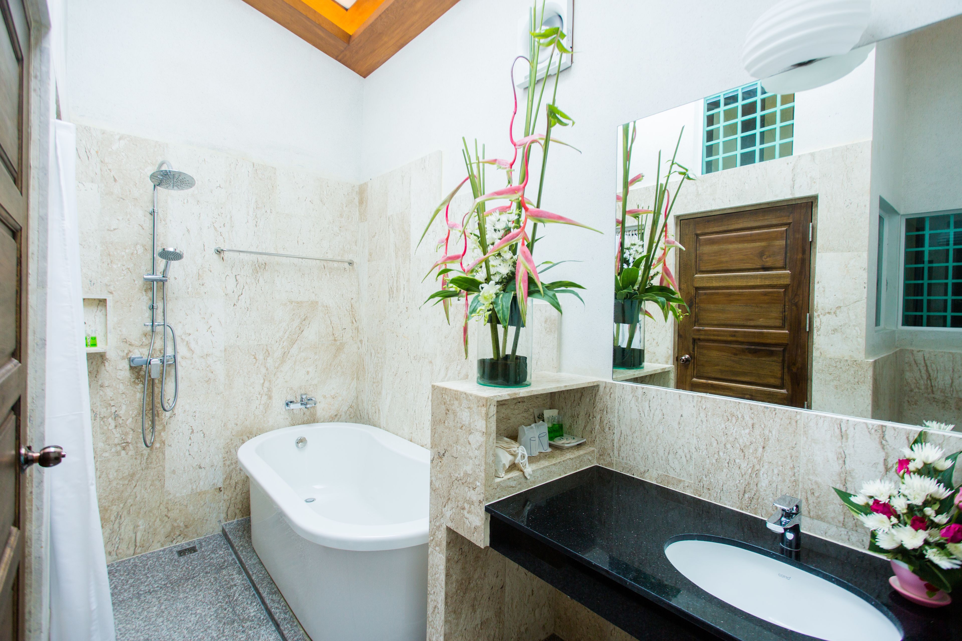 A bathroom with a bathtub, a sink, a shower, and a mirror.