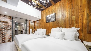 Een hotelkamer met twee bedden, houten wanden, een moderne kroonluchter en een ingelijst schilderij aan de muur.