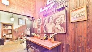 Een houten interieur met een bar, potplanten, ingelijste foto's en een neonreclame.