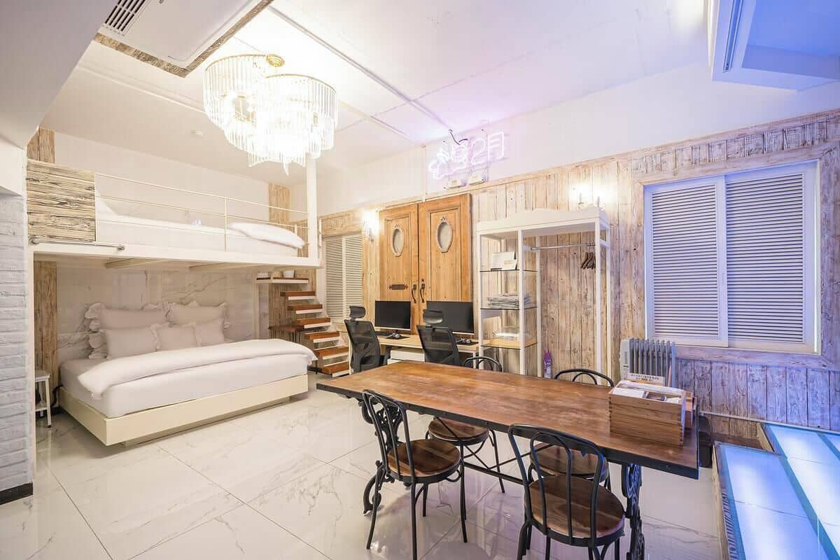 Quarto compacto com beliche, área de jantar com mesa e cadeiras de madeira e um candelabro.