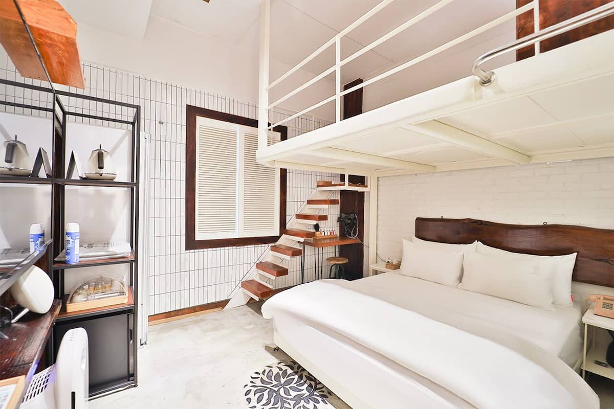 Quarto com beliche, escrivaninha com cadeira, prateleira com utensílios de cozinha e tapete estampado.
