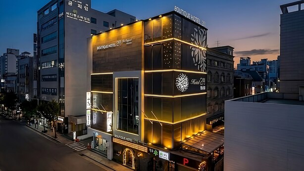 Een modern hotelgebouw met verlichte reclame, grote ramen en een opvallend logo.