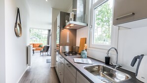 Une cuisine moderne dotée d’appareils électroménagers en acier inoxydable, d’un évier à deux bacs et d’une fenêtre laissant entrer la lumière naturelle.