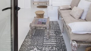A modern living room with a sofa, a patterned rug, a coffee table, and a hanging light fixture. - Akassa Alojamientos Bioclimáticos (Pinofranqueado)