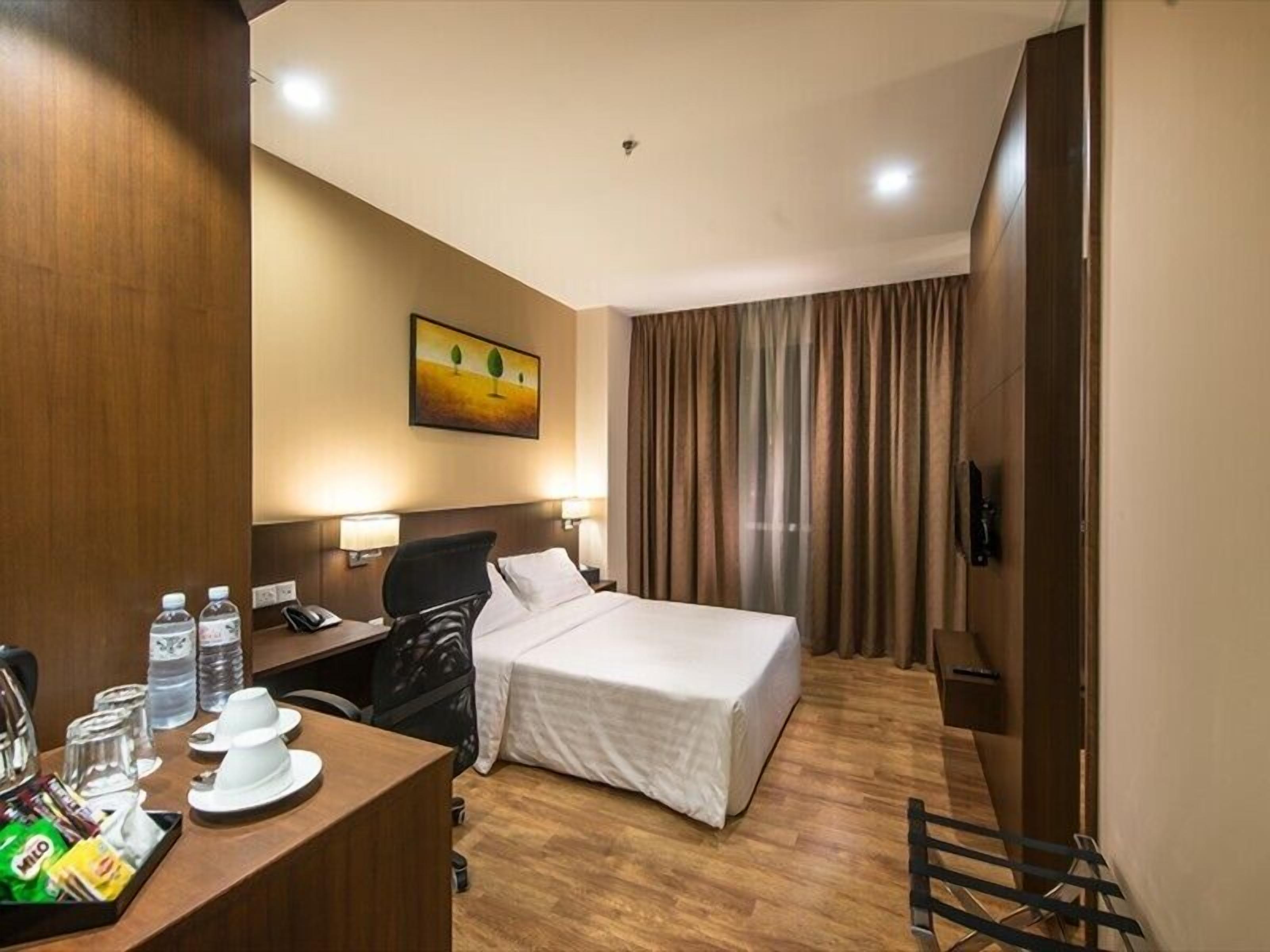 Habitación de hotel con cama, escritorio, silla, teléfono y un cuadro en la pared.