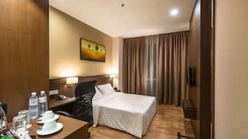 Habitación de hotel con cama, escritorio, silla, teléfono y un cuadro en la pared.