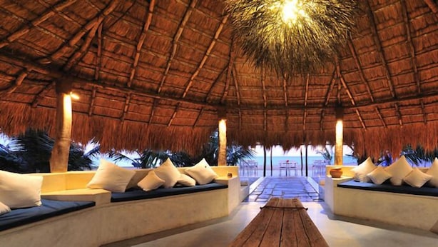 A thatched-roof lounge area with seating and a view of the beach.