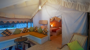 A cozy tented accommodation with a sofa set, a small round table, and a chair.