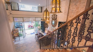 Una escalera con barandales metálicos ornamentados, suelo de madera y lámparas colgantes de estilo farol.