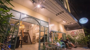Un área de estar interior con sillas de mimbre y una escalera que lleva a un nivel superior.