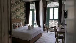 Un dormitorio con cama, dos sillas, una mesa y una lámpara decorativa colgante.