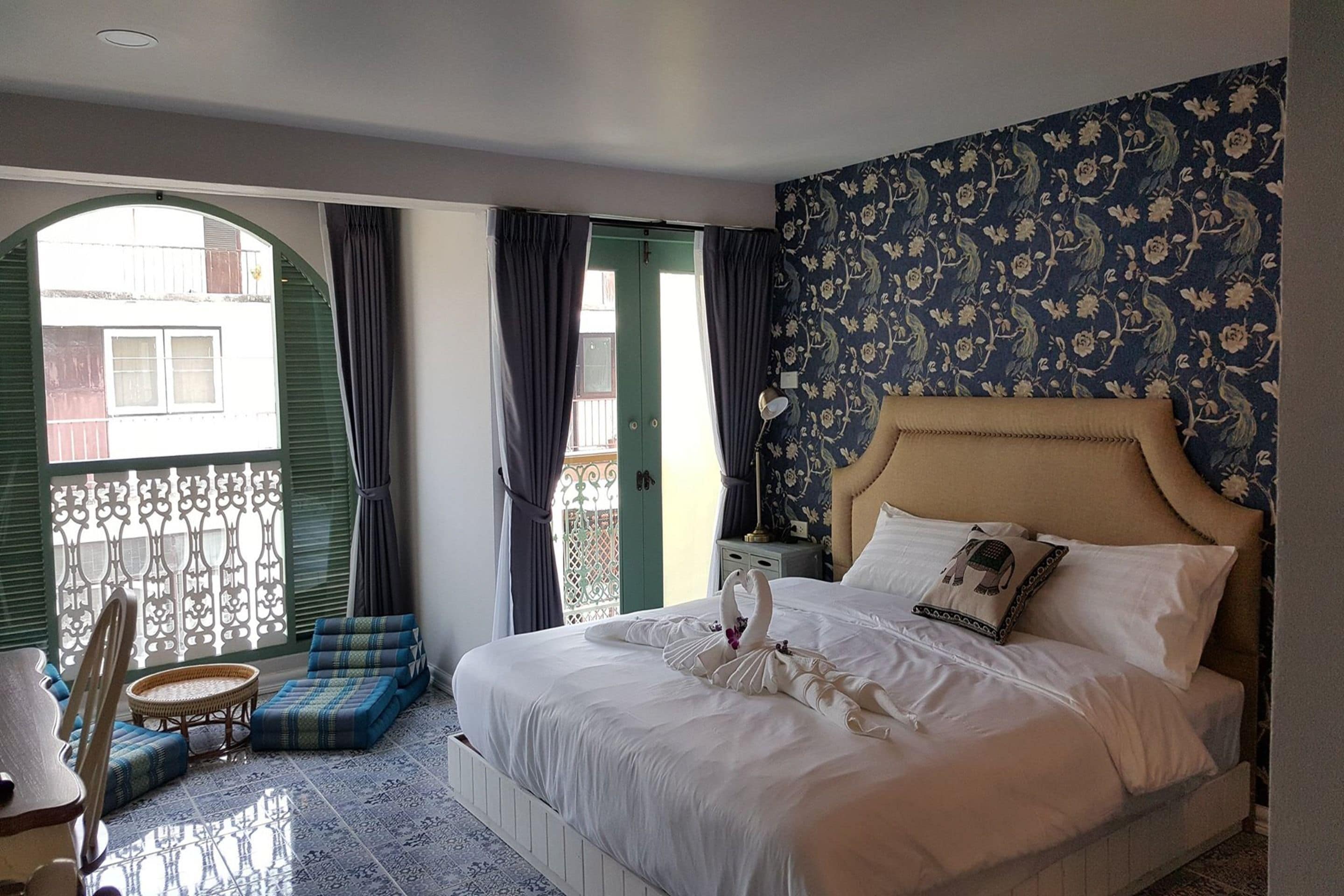 A hotel room with a bed, a small table, a chair, and a balcony with a view.