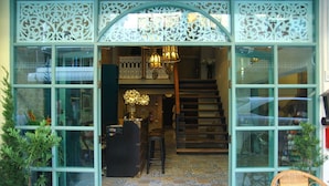 Entrada de un hotel boutique con suelo de baldosas, una escalera y un arco decorativo.