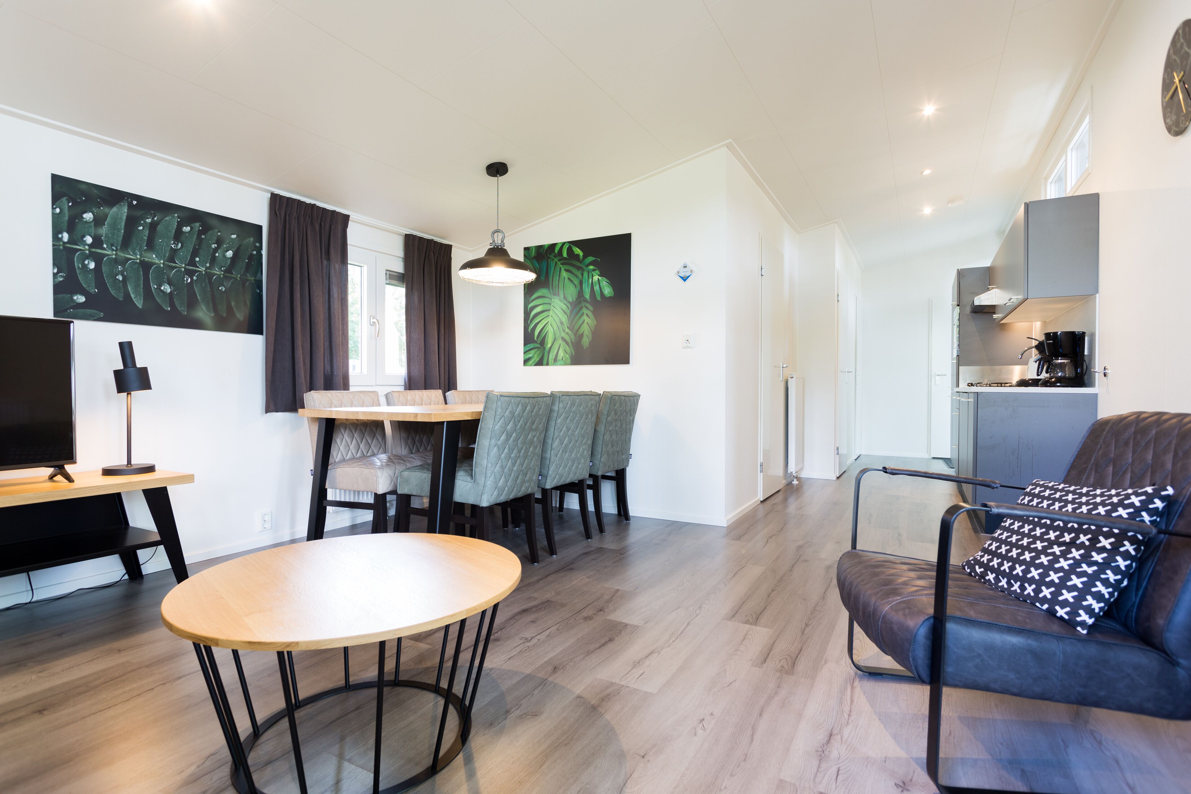 A modern living room with a dining area, a kitchen, and a seating area.