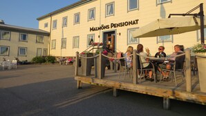 Un edificio con un letrero que dice 'Malmö Pensionat' y mesas y sillas para estar al aire libre.