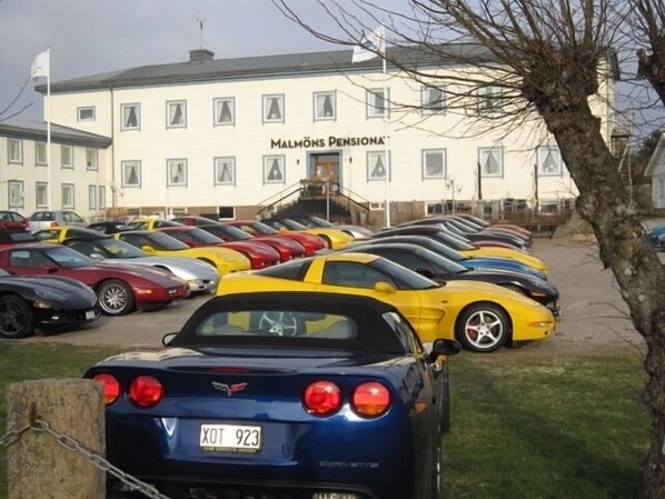 Una fila de coches deportivos estacionados frente a un edificio con un letrero que dice 'Malmö Pension'.