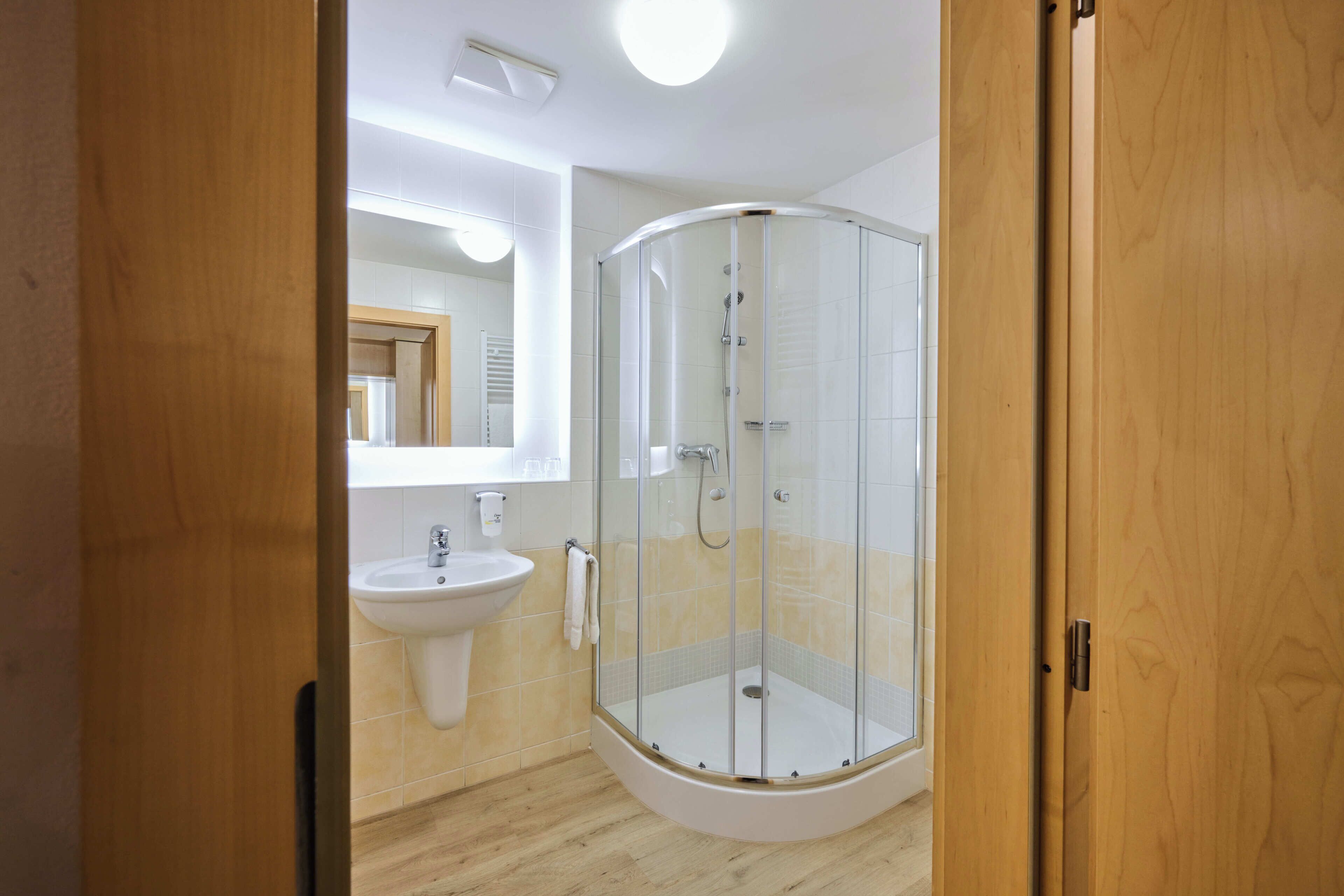 A bathroom with a glass-enclosed shower, a sink, and a mirror.
