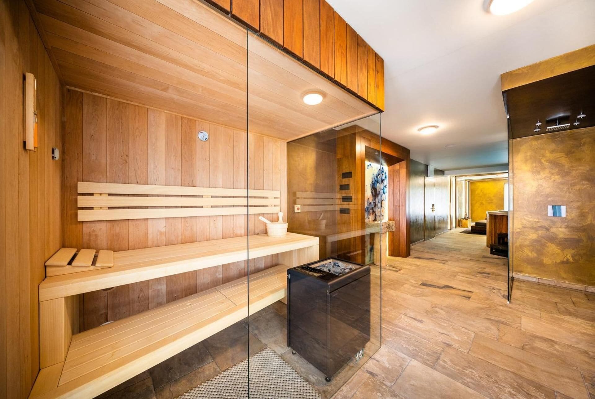 Un sauna avec des bancs en bois et une paroi en verre.