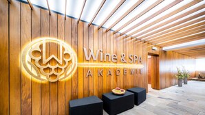 A reception area with a wooden wall and a sign that reads "Wine & Spa Academy".