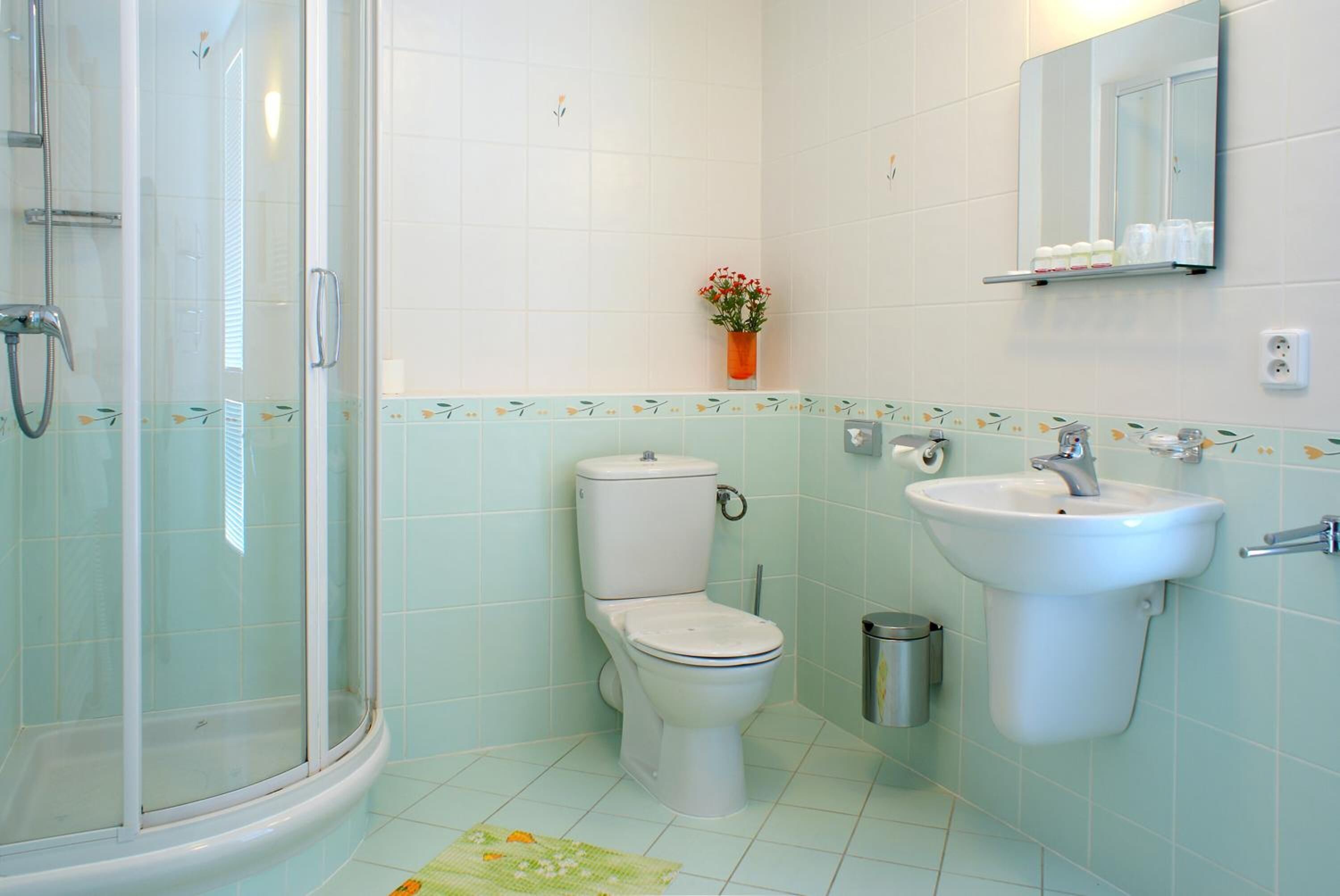 A bathroom with a glass-enclosed shower, a toilet, and a sink.