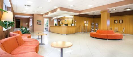 Un hall d’entrée avec un comptoir de réception, des espaces d’attente et une machine à café.