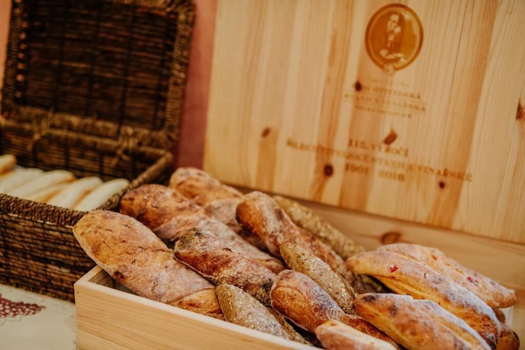 En trækasse fyldt med forskelligt brød, blandt andet baguette og boller.