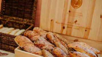 En trækasse fyldt med forskelligt brød, blandt andet baguette og boller.