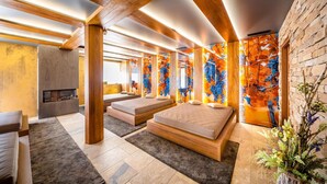 A modern room with wooden beams, a fireplace, two beds, and colorful abstract wall art.