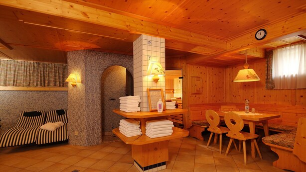 Un intérieur en bois comprenant un coin repas, une salle de bain avec un mur carrelé et un lit avec une literie à rayures.