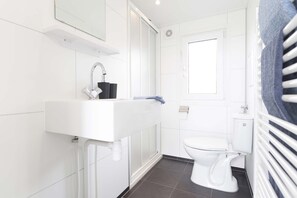 A modern bathroom with a white sink, a mirror above it, a toilet, and a towel rack. - TopParken Recreatiepark het Esmeer (Aalst)