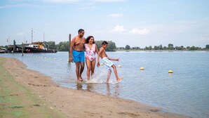 Una playa con un muelle y barcos al fondo.