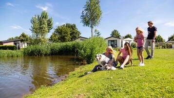 Guests can enjoy a serene outdoor setting with a grassy area adjacent to a calm body of water.
