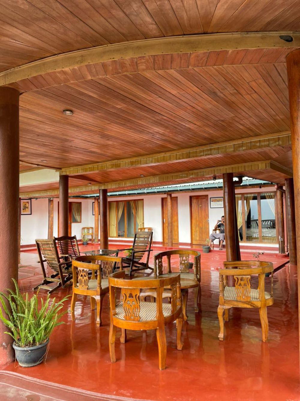A covered outdoor seating area with wooden chairs and a potted plant.