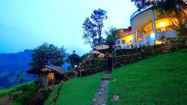 A hillside hotel with a thatched-roof structure and a stone pathway leading to a covered seating area. - The Hideaway Ella (Makulella)
