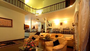 A spacious living room with multiple sofas, a coffee table with flowers, a staircase, and a dining area. - The Hideaway Ella (Makulella)