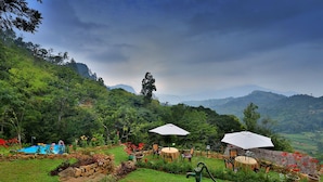 A lush garden with a pool, outdoor seating, and a scenic mountain backdrop. - The Hideaway Ella (Makulella)