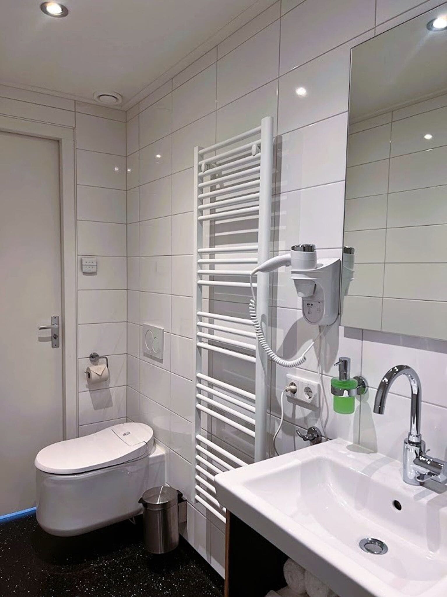 A modern bathroom with a toilet, sink, and towel rack.